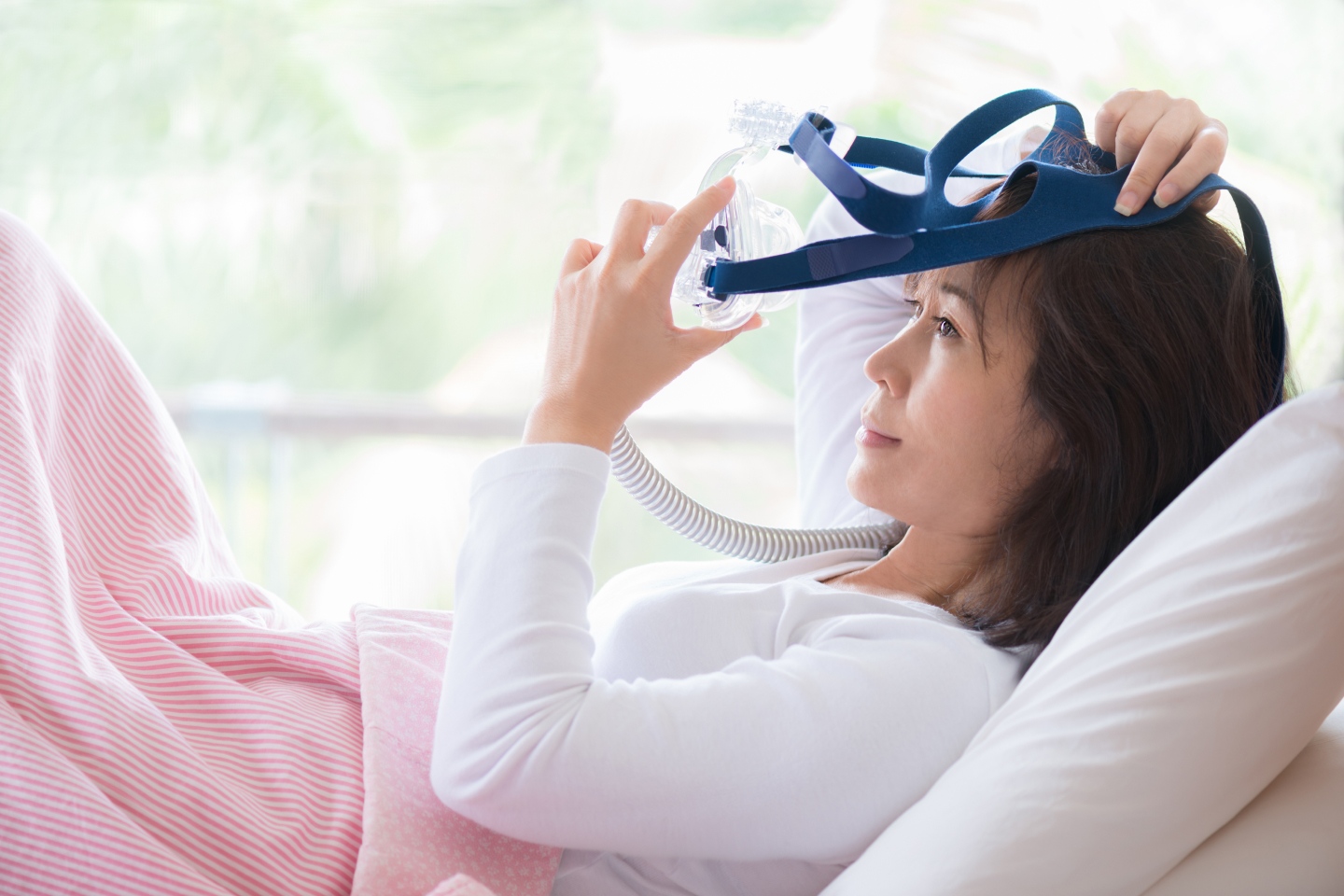 Person in bed putting on a CPAP machine representing Resmed technologies