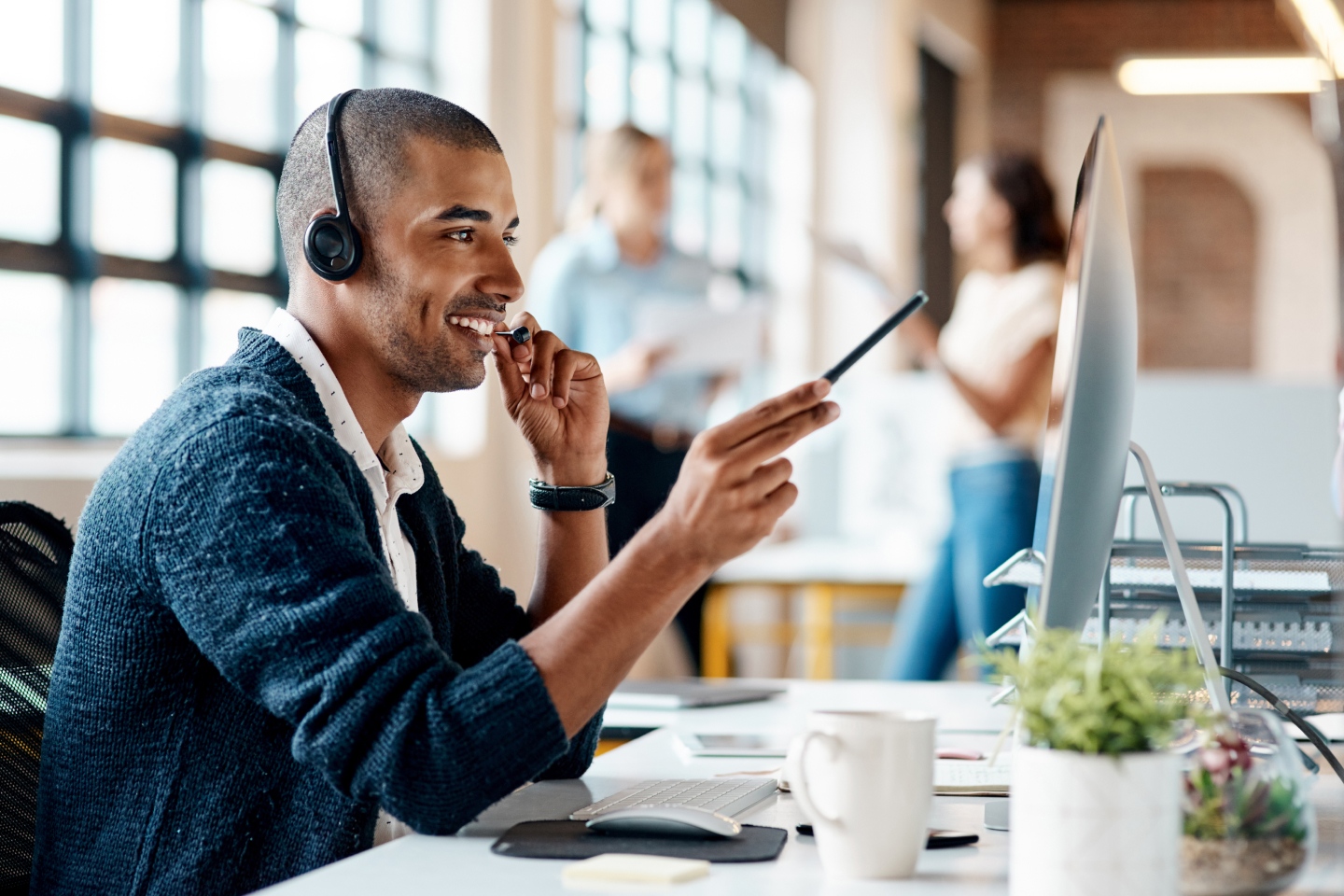 Man with headset talking on phone at desk, representing Comms Group