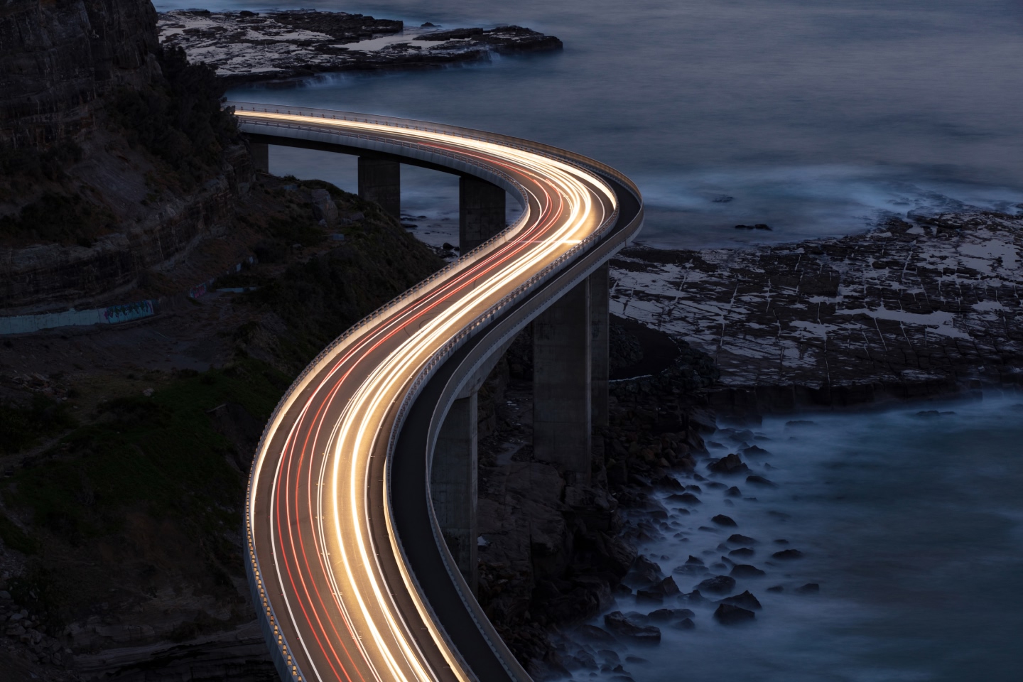 Fast moving cars on a bridge at night, showing as a blur of light, representing infrastructure