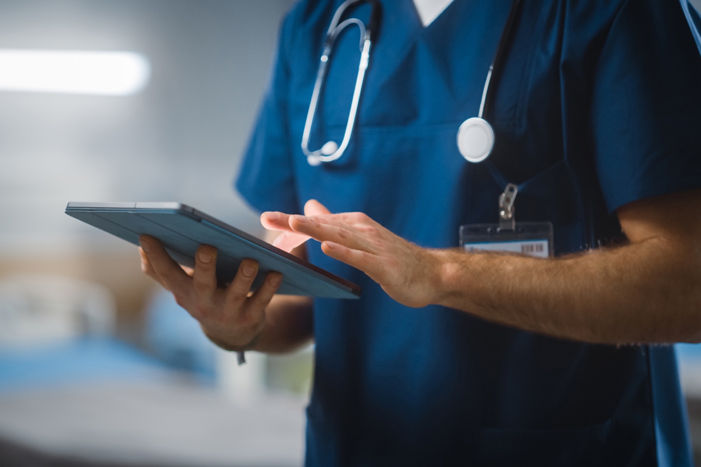 Doctor in scrubs and a stethoscope holding a tablet
