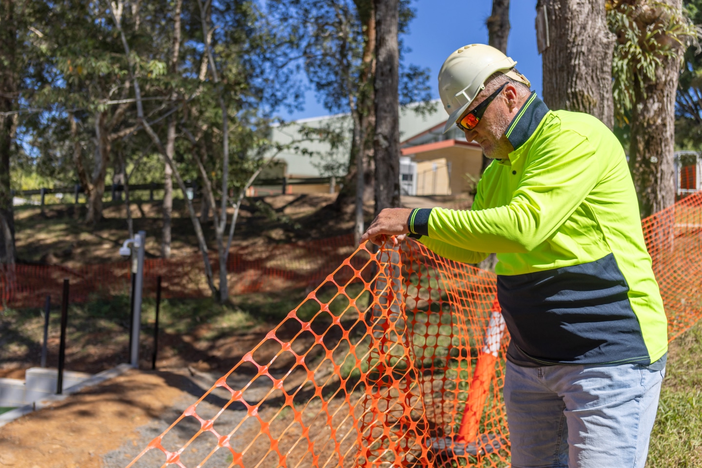 Construction worker assembling fence for development of essential infrastructure like NSW Schools