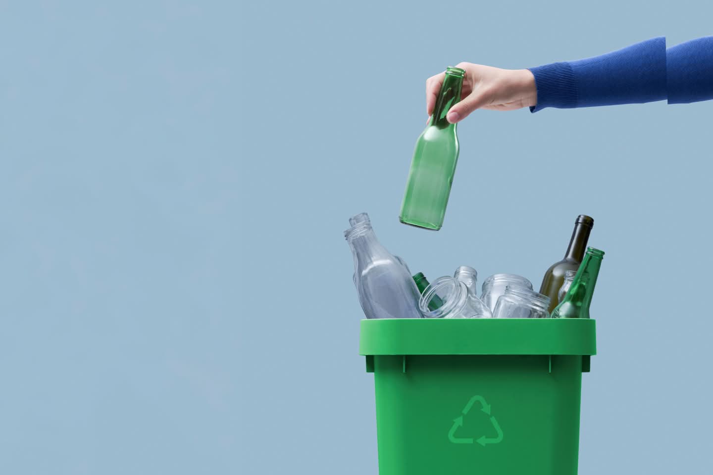 Hand throwing a bottle in a recycling bin, representing Cleanaway