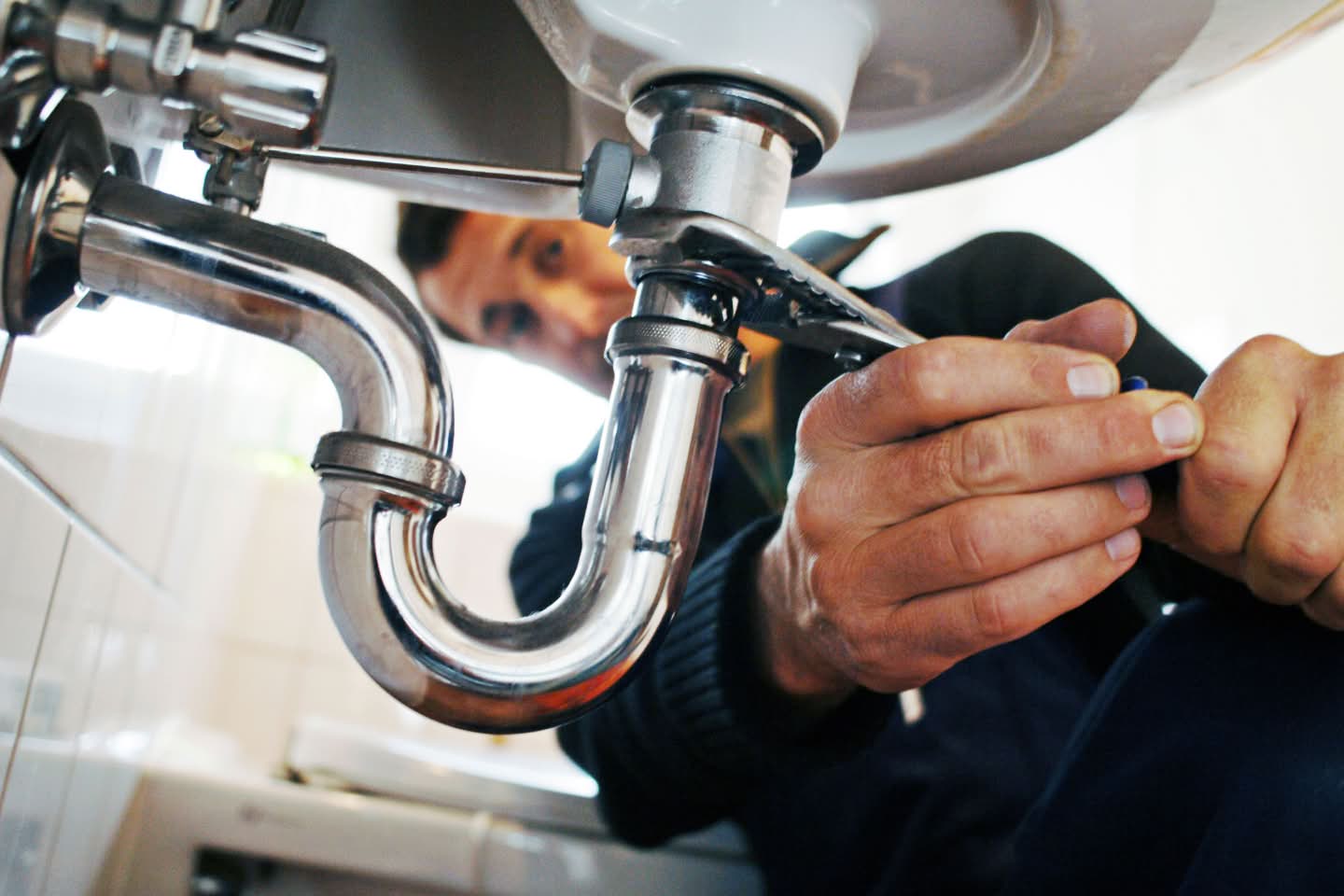 Man repairing a bathroom sink, representing Reliance