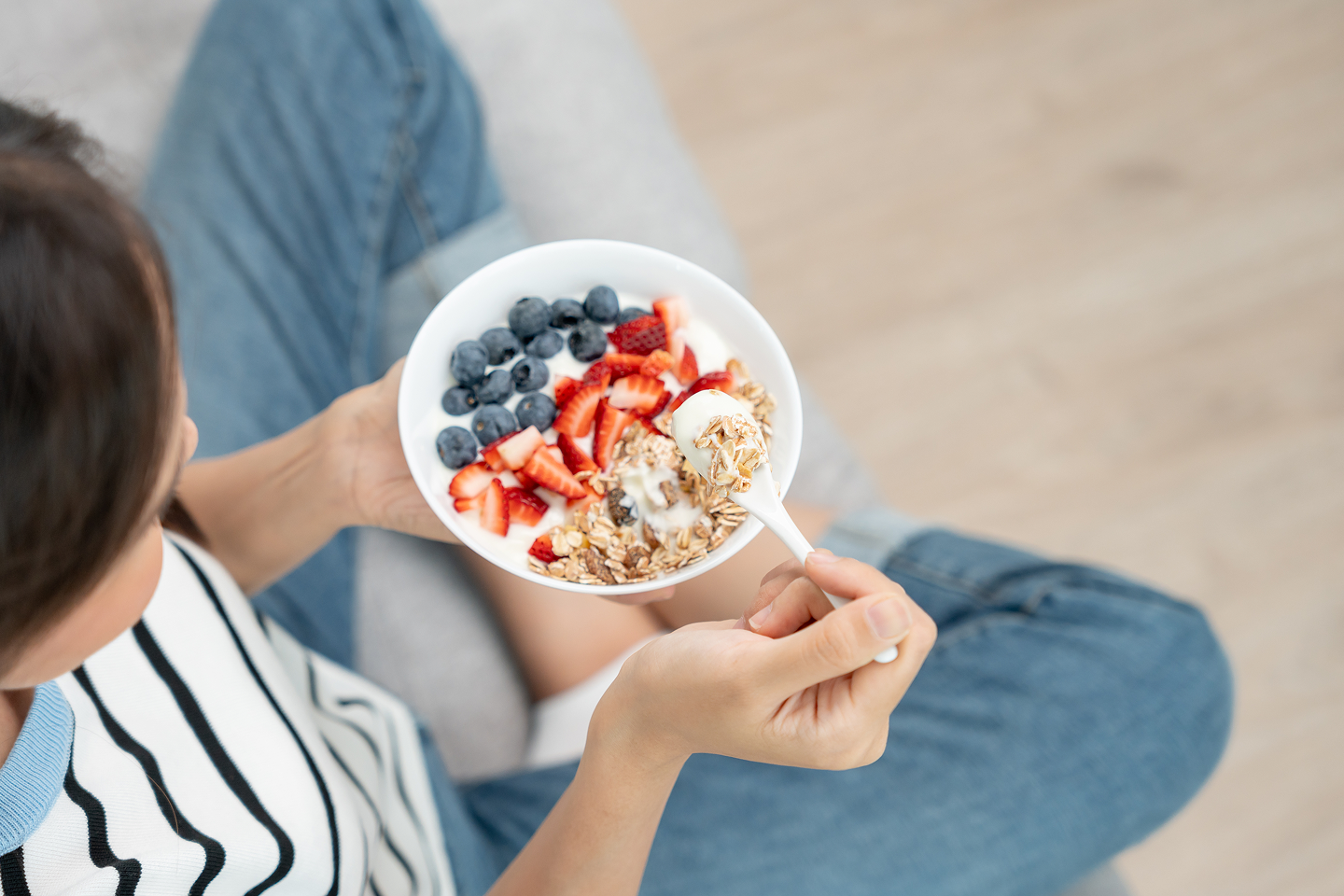 Photo from above of a woman eating cereal with fruit
