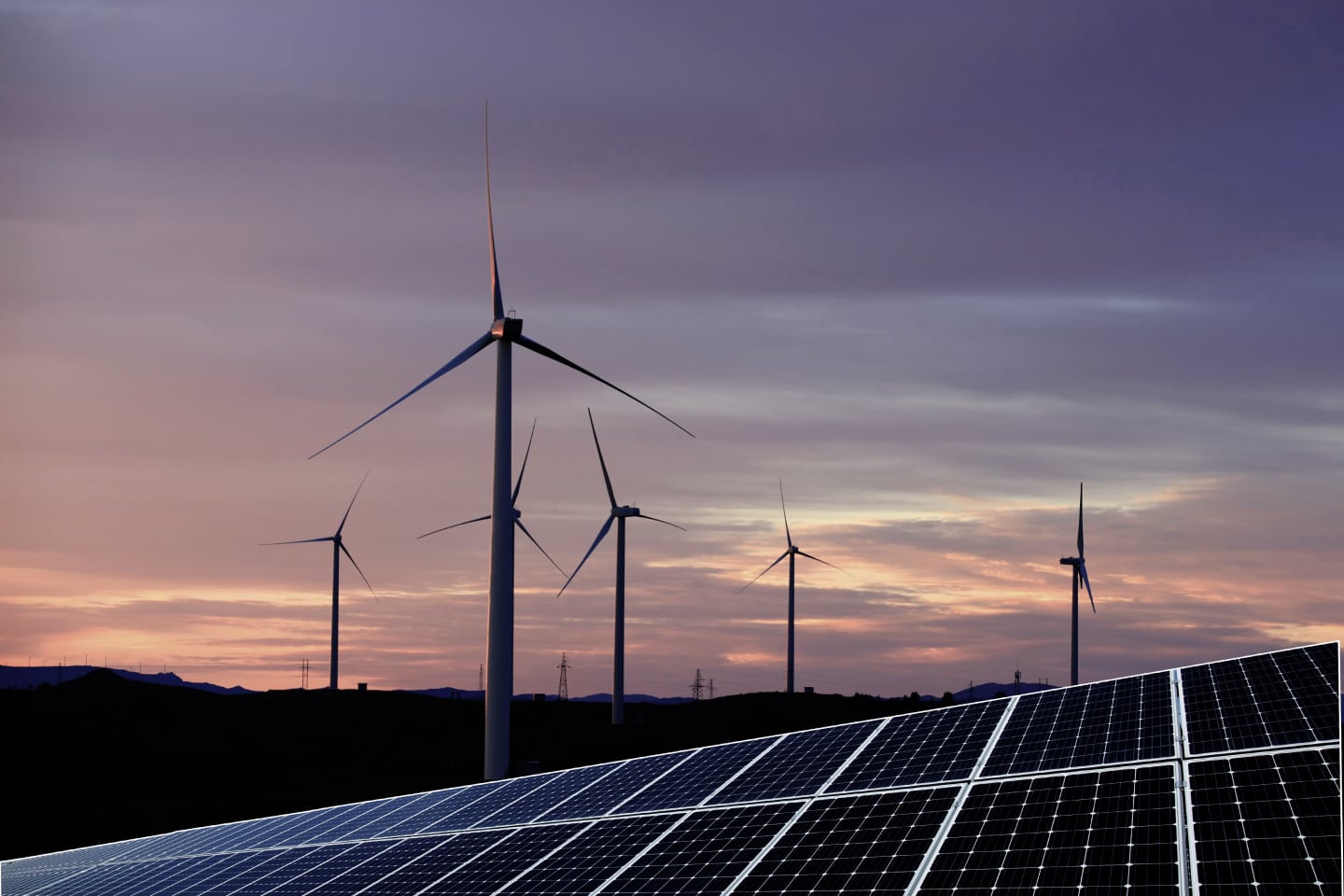 A field of solar panels and wind turbines generating green renewable energy as an alternative to fossil fuels