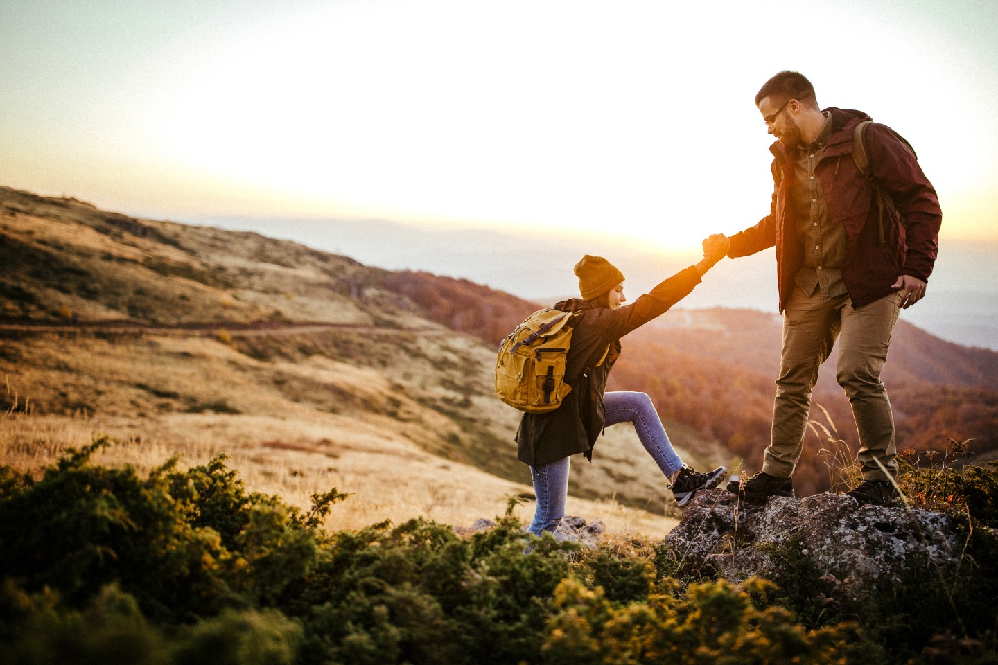 Couple where one is helping the other climb up a scenic path