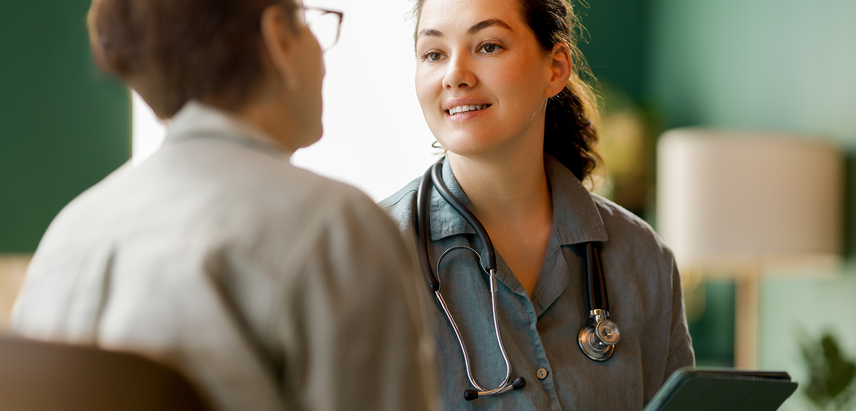Female doctor in scrubs talking to a patient
