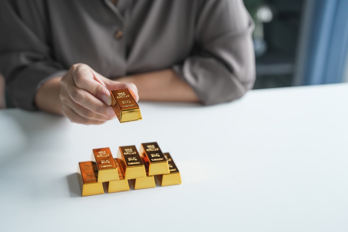 Man stacking gold ingots in a pyramid of bars