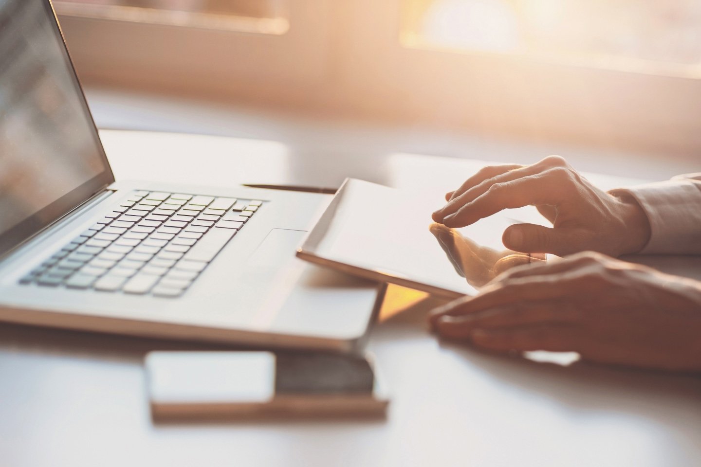 Person on a tablet with their phone and laptop at hand