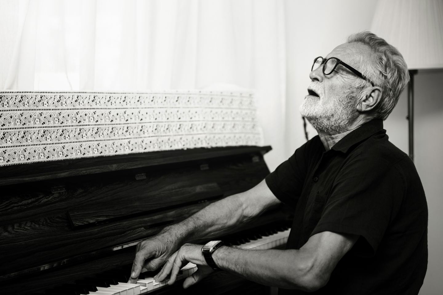 Black and white photo of a retired man playing the piano