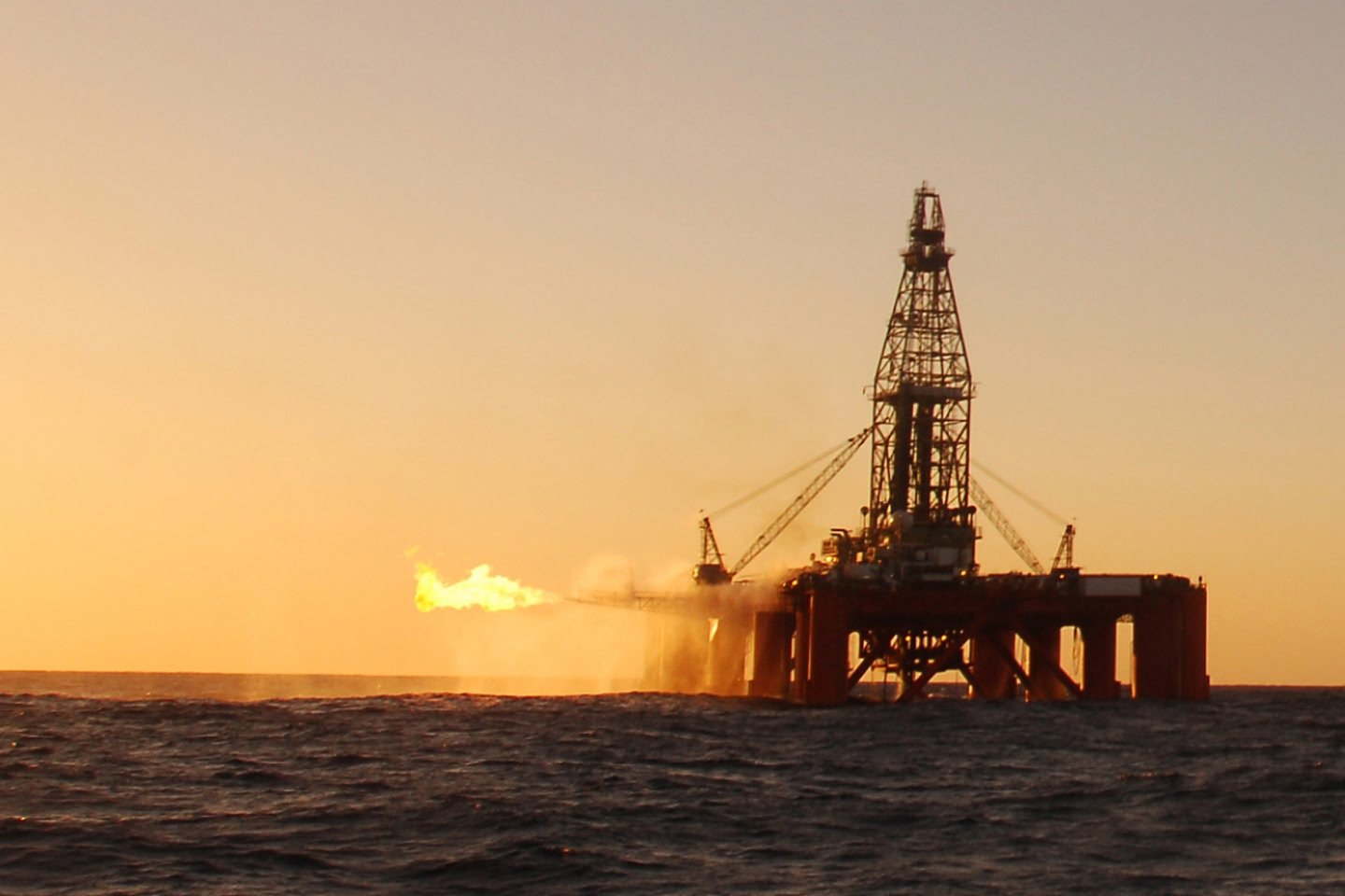 Offshore oil rig at sea in at sunset