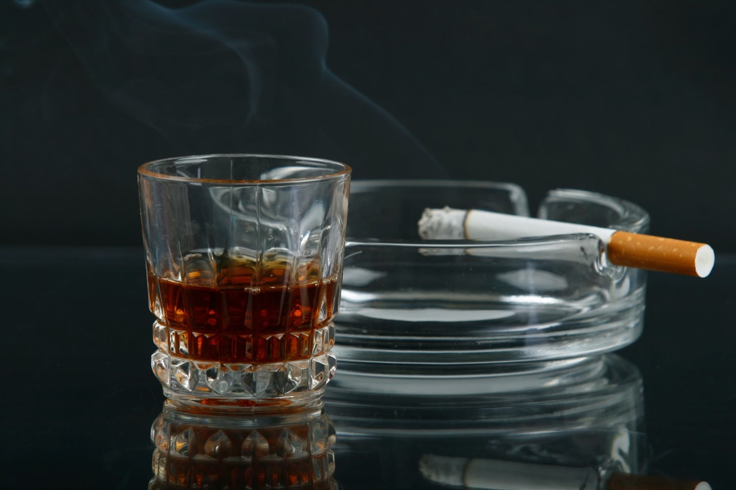 Cigarette and glass of whiskey showing industries that cause social harm